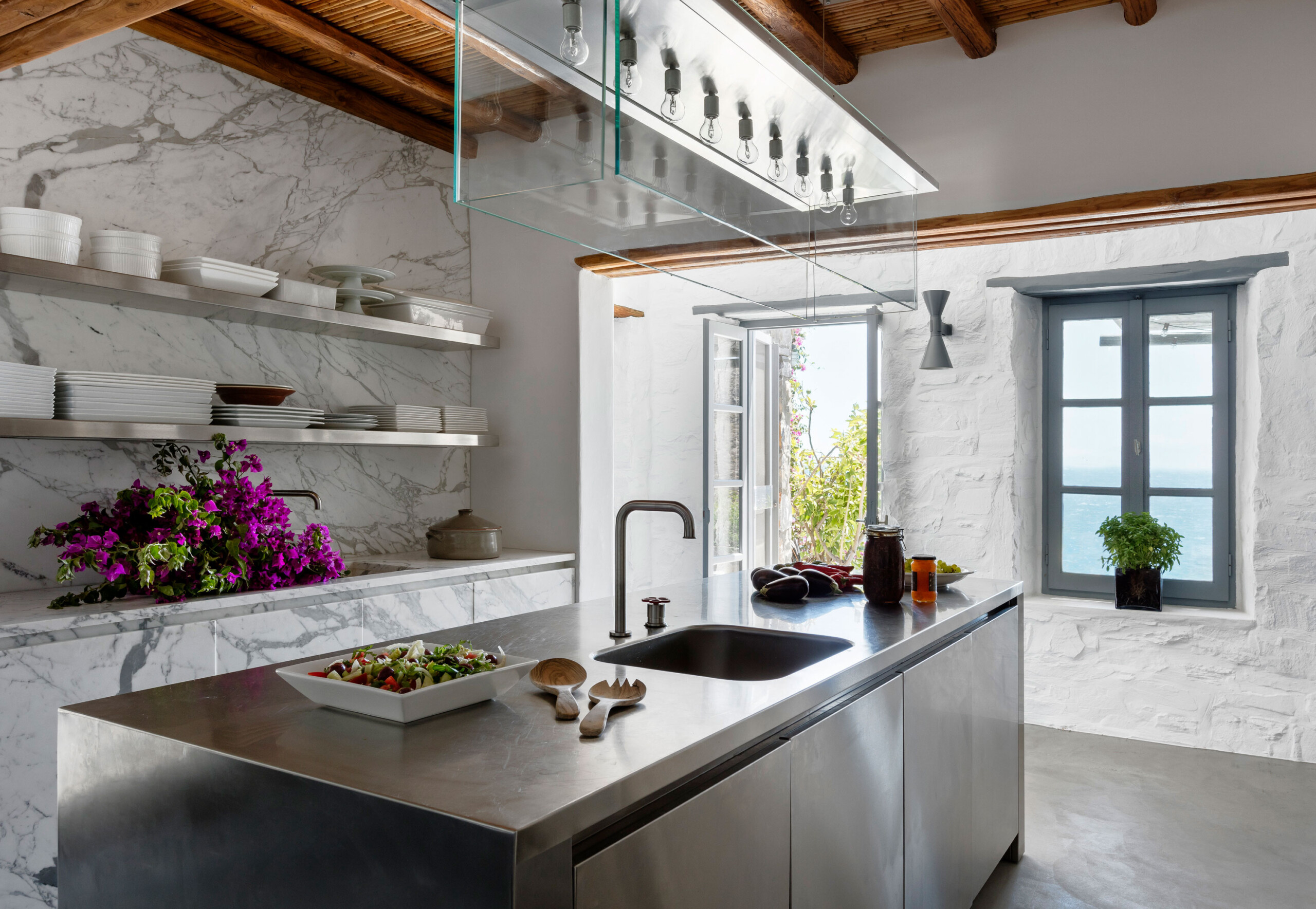Cycladic Villa - Scandinavian-inspired modern kitchen with white marble and stainless steel accents....
