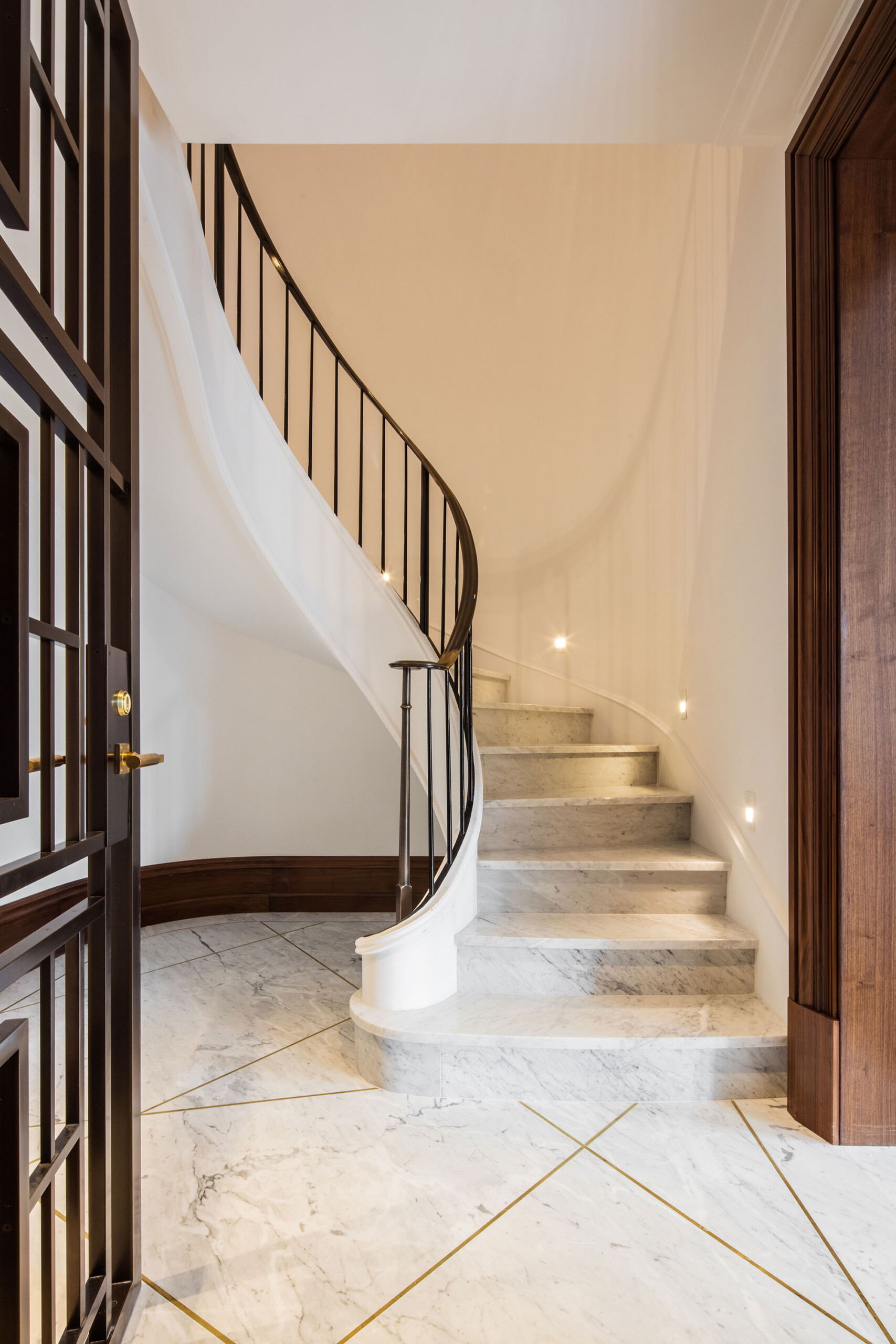 155 East 79th Street - Curved white marble staircase of New York condo with dark contrasted railing....