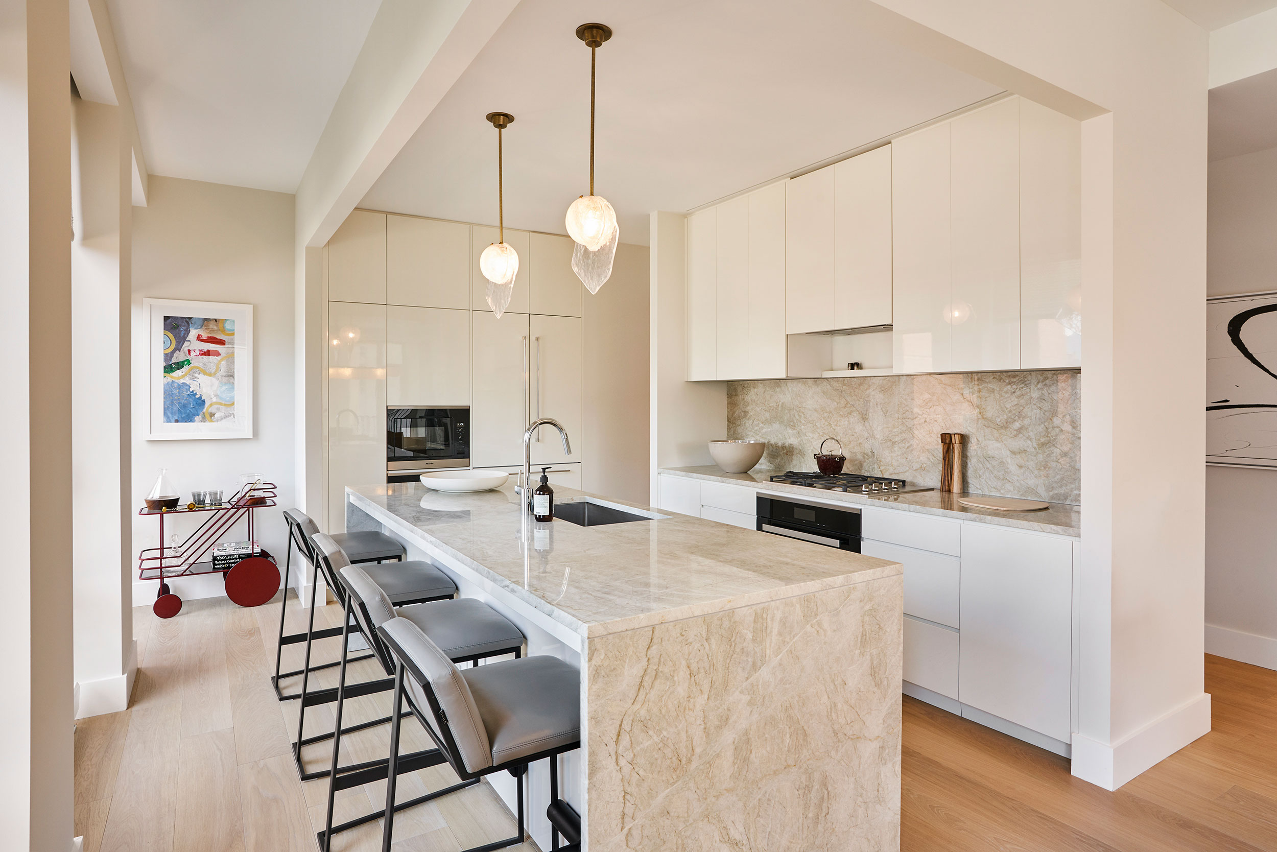 The Park Loggia - Luxury kitchen with modern marble kitchen island and backsplash. Globe pendant...