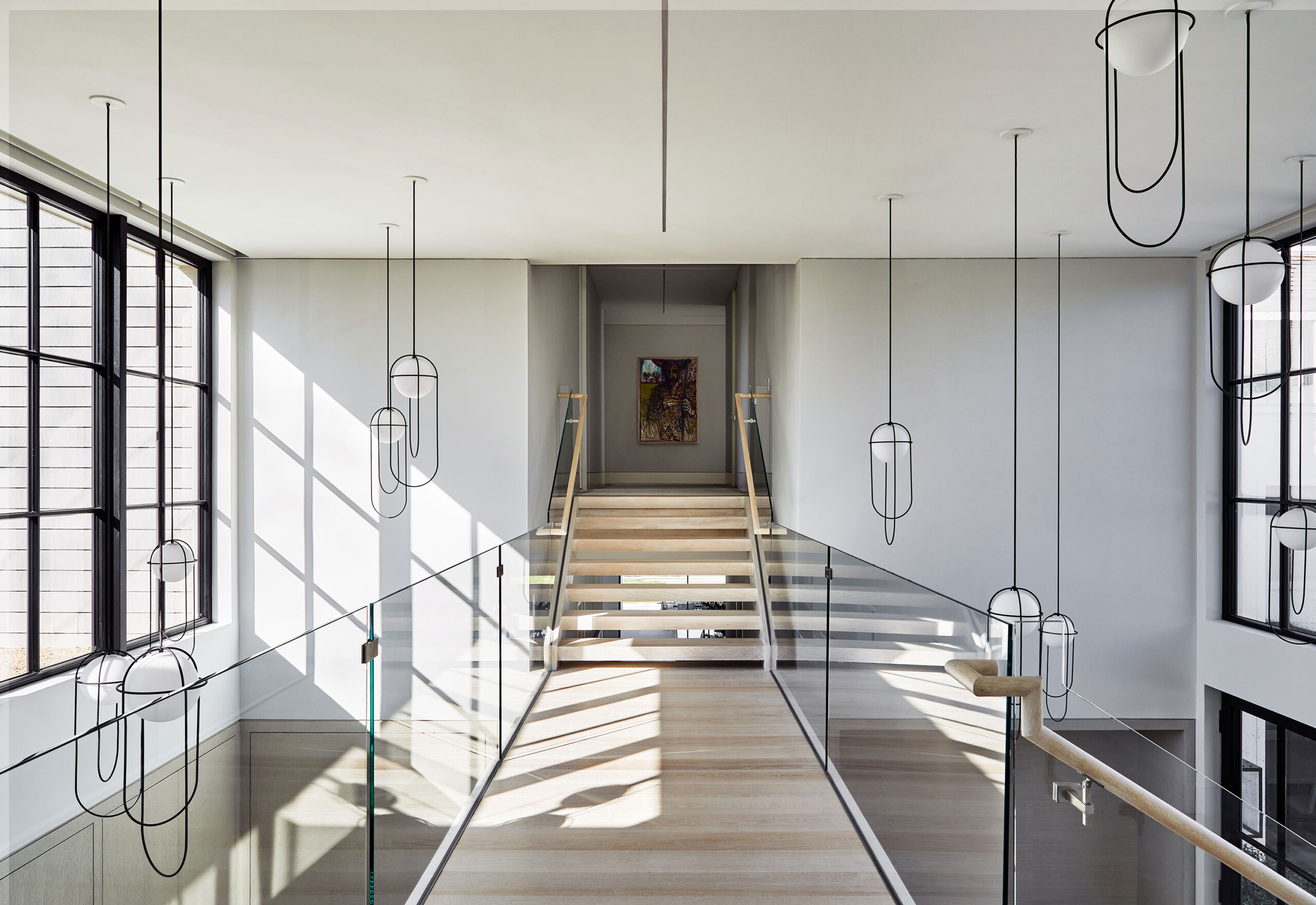 Southampton Estate - Pembrooke & Ives - Second-story lifted hallway flocked by glass railings and...