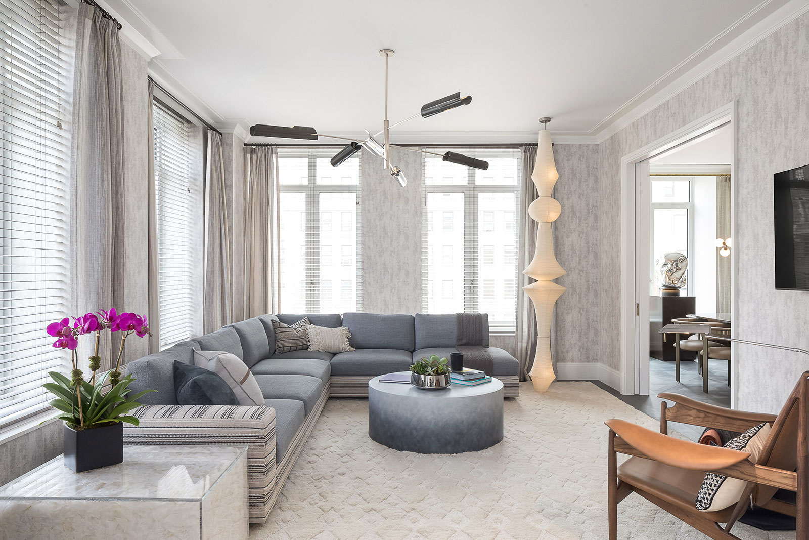 1010 Park Avenue - Living room of New York home with grey and blue tones, featuring L-shaped sofa,...