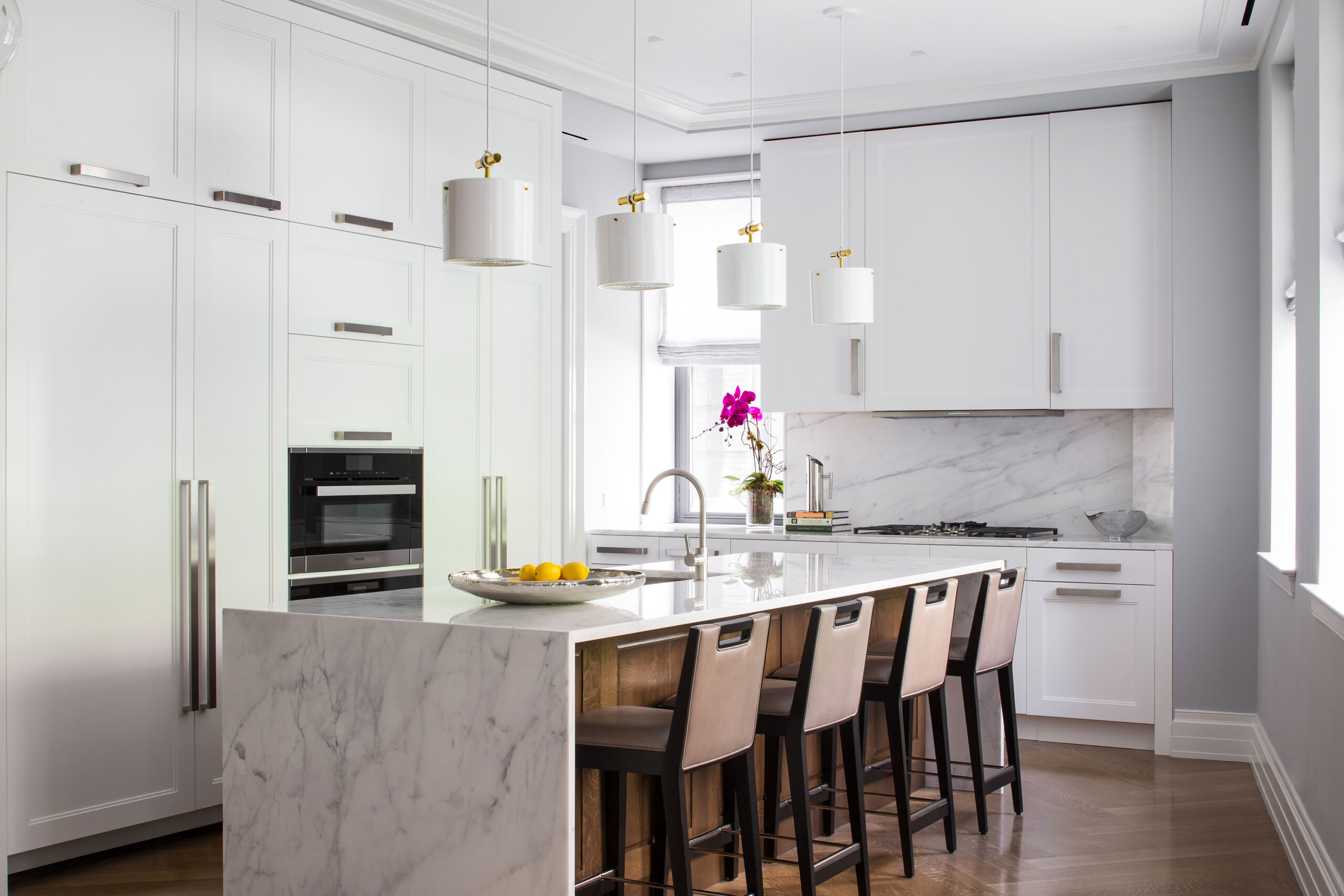 The Astor - Modern kitchen in The Astor, with white marble countertop and backsplash, white pendant...