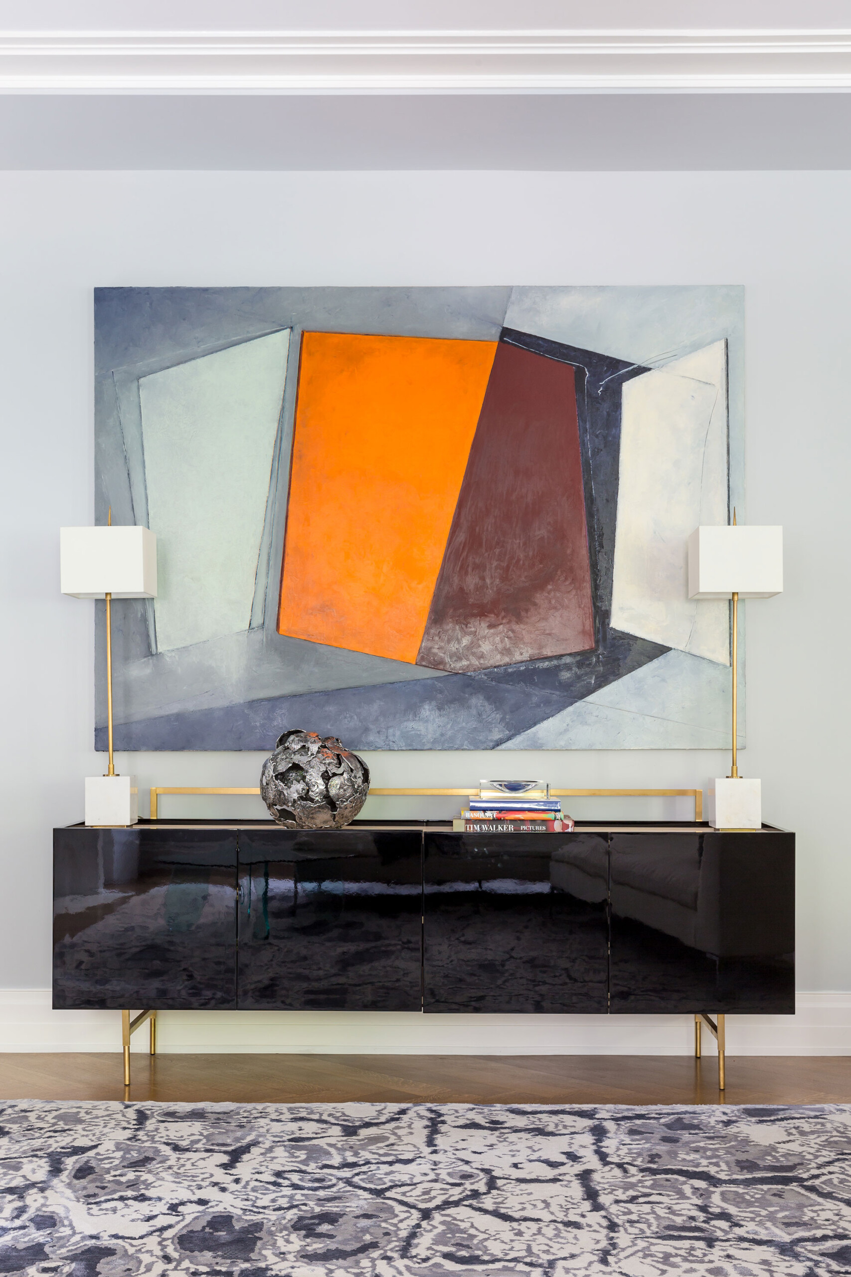 The Astor - Entryway detail with modern art and glossy black and brass credenza. Interior design...