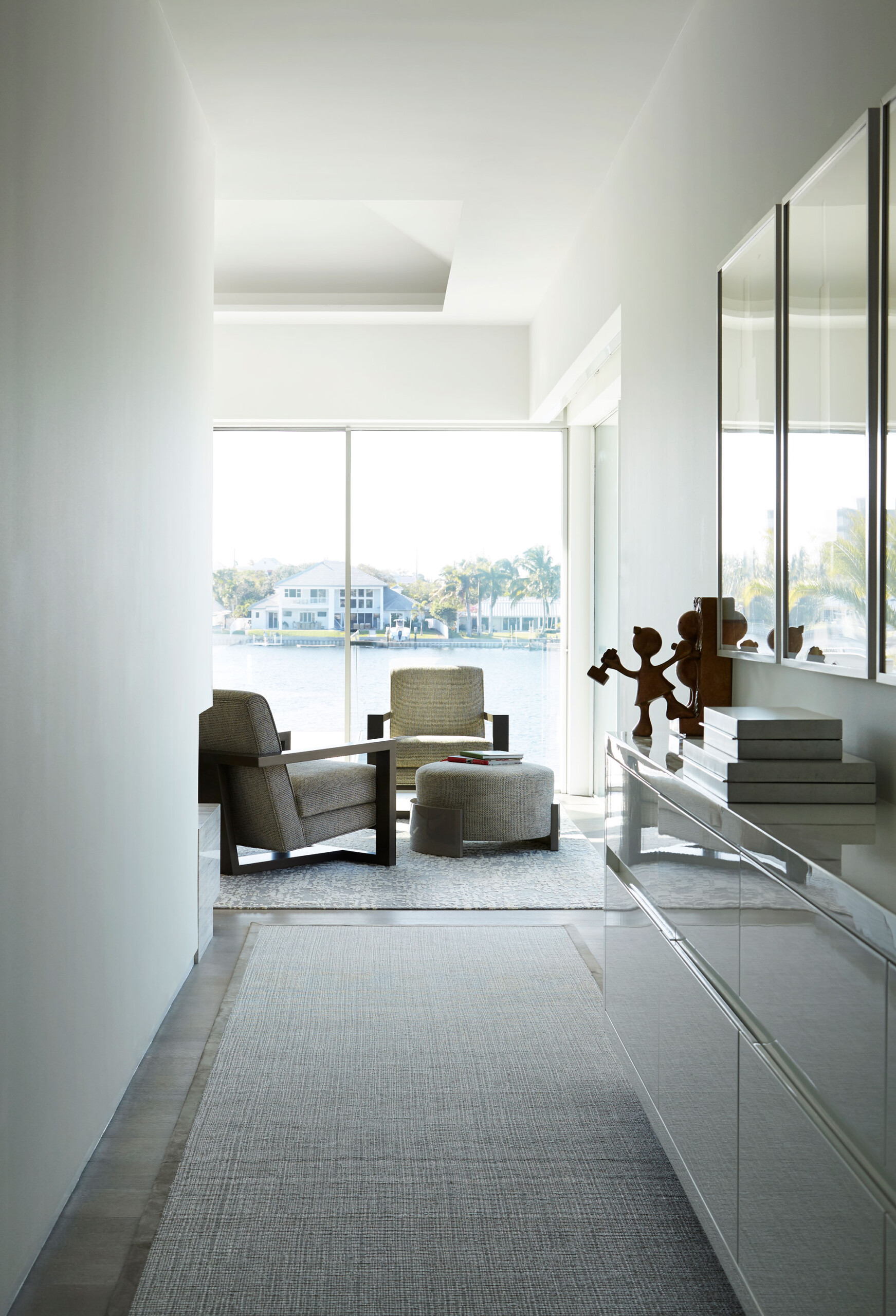Lost Tree Way - Hallway of modern Palm Beach, FL home with textured carpet, mirrored credenza and...