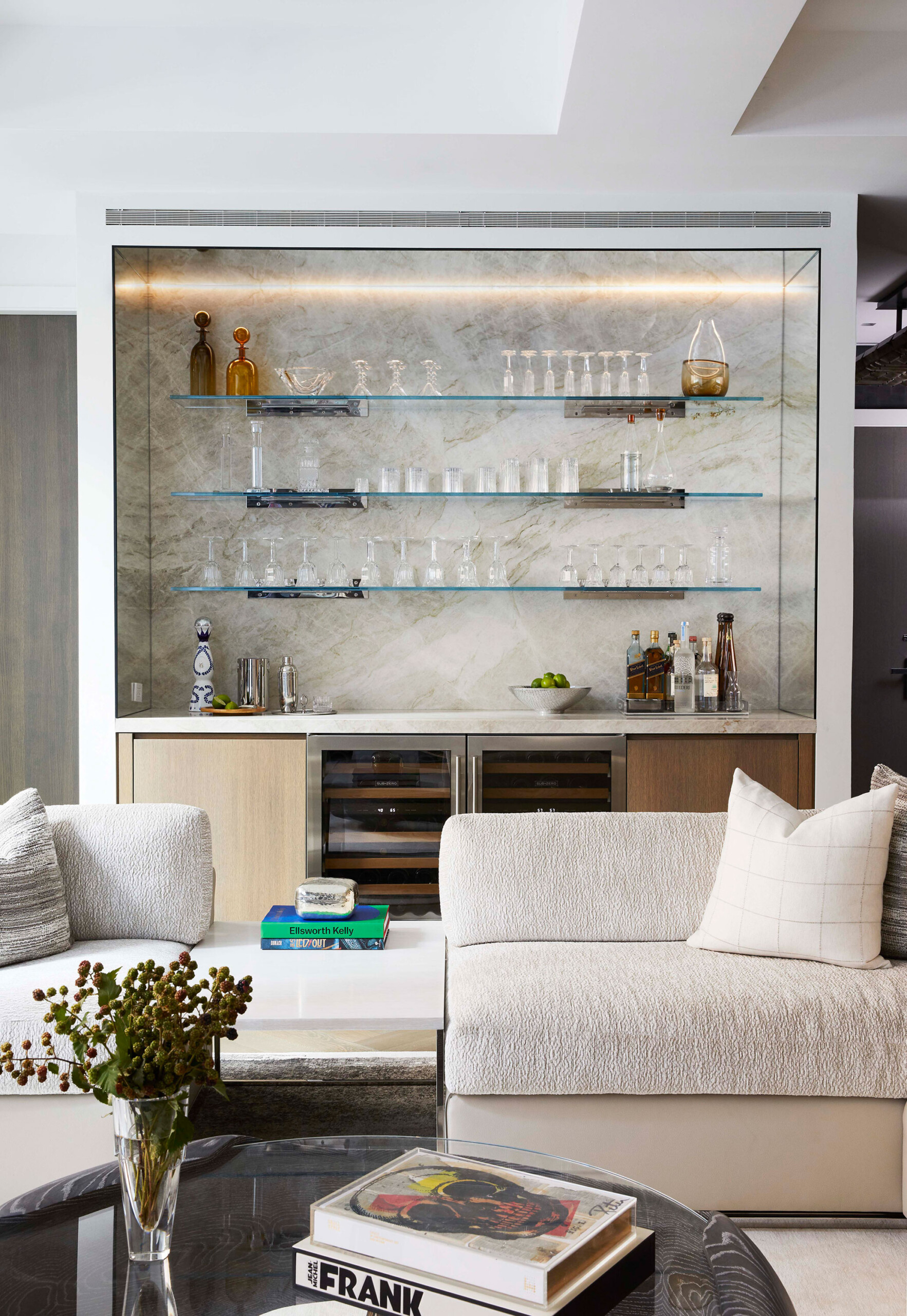 Leonard Street - Home bar with glass shelving and light wood cabinetry beside modern living room...