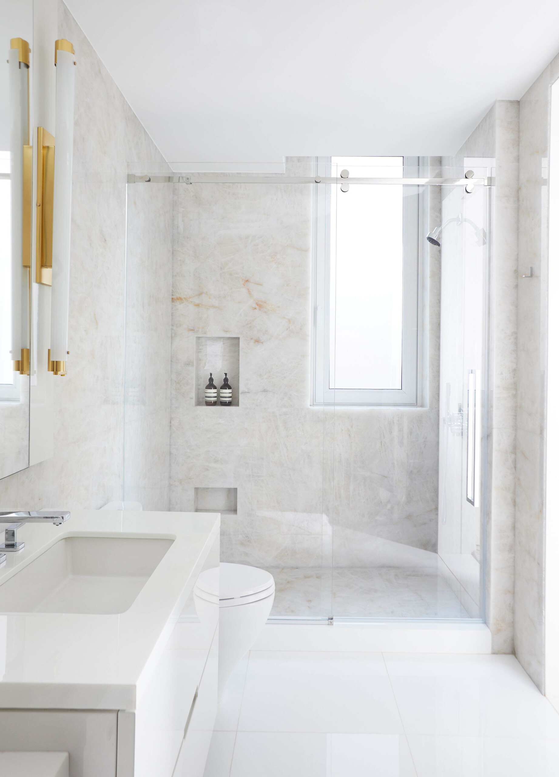 Leonard Street - White marble bathroom with brass lighting accent. Interior design by Pembrooke...