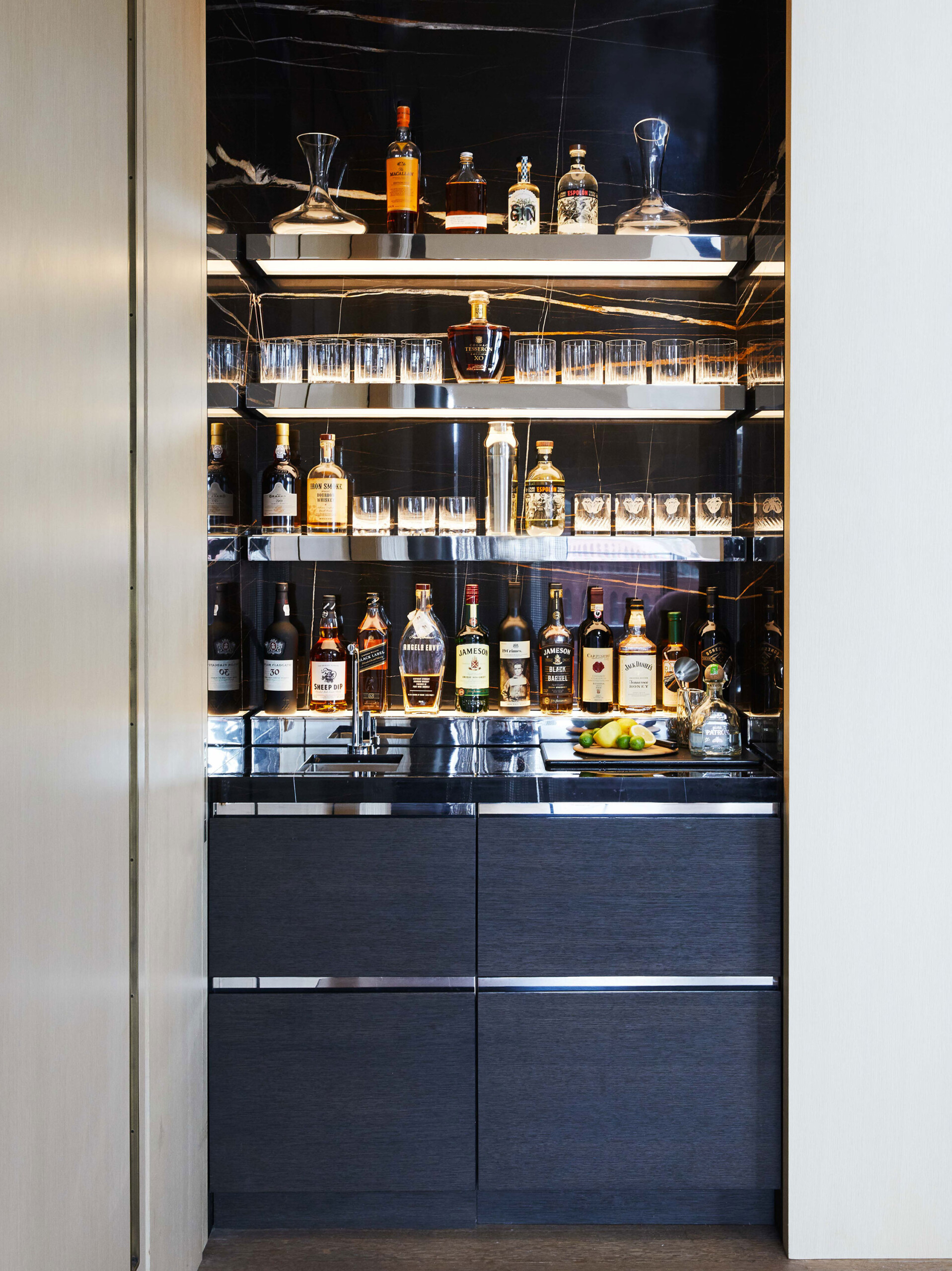 West Village Penthouse - Pembrooke & Ives Illuminated shelving in modern bar of New York home....