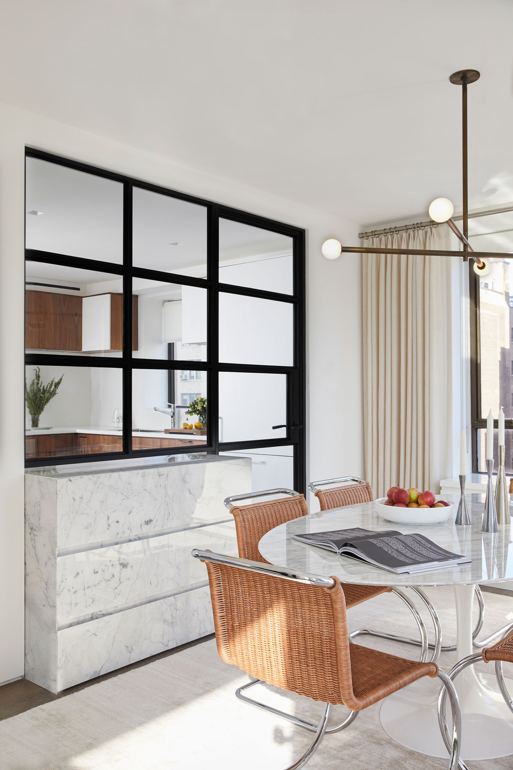 Uptown Pied-á-Terre - Mid-century modern dining room with round white marble table, woven chairs,...