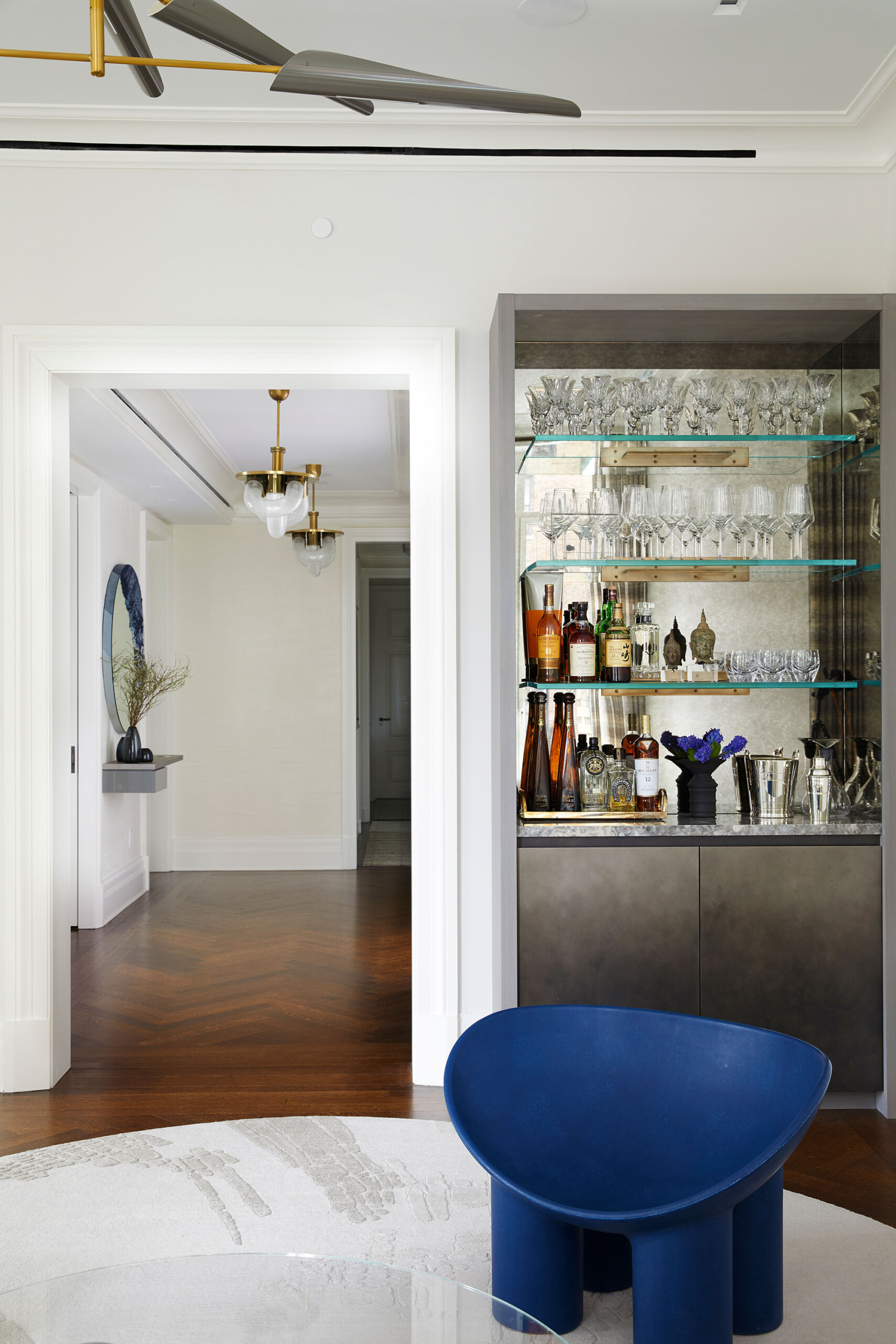 East End Avenue - Home bar in luxury New York apartment featuring glass shelving and mirrored wall....