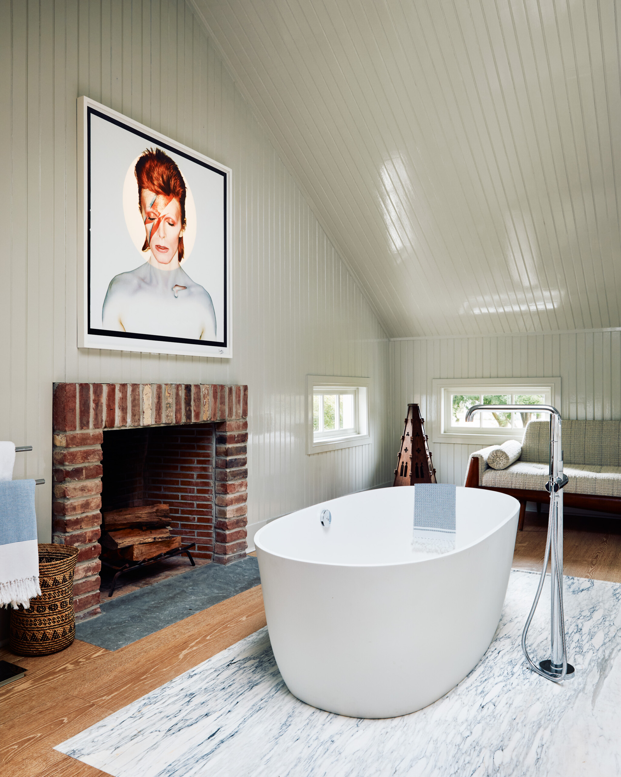 Hamptons Interior Design by Pembrooke & Ives. Primary bath with stand-alone tub and brick fireplace.