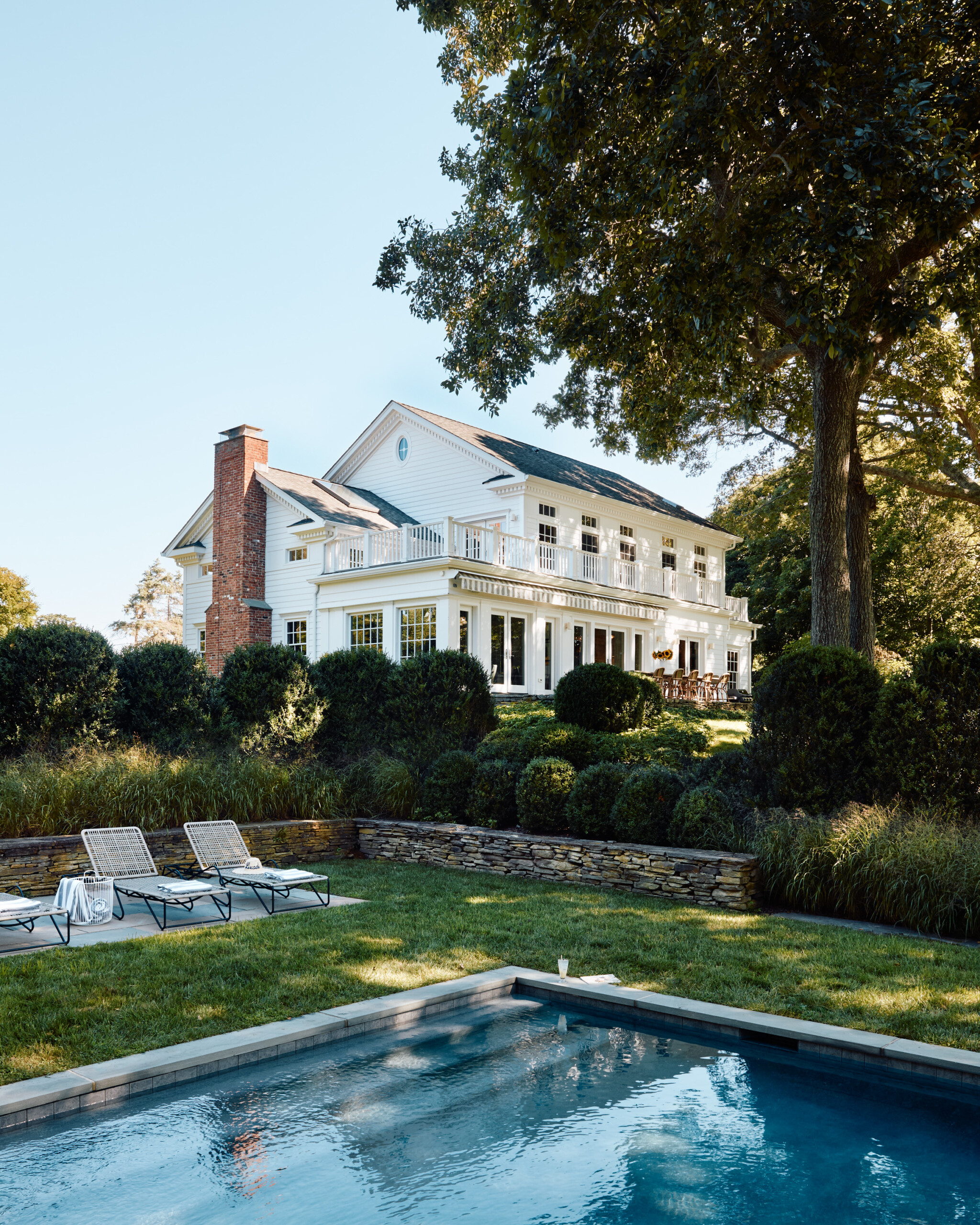 Hamptons Interior Design by Pembrooke & Ives. Exterior of Hamptons home with pool and garden.