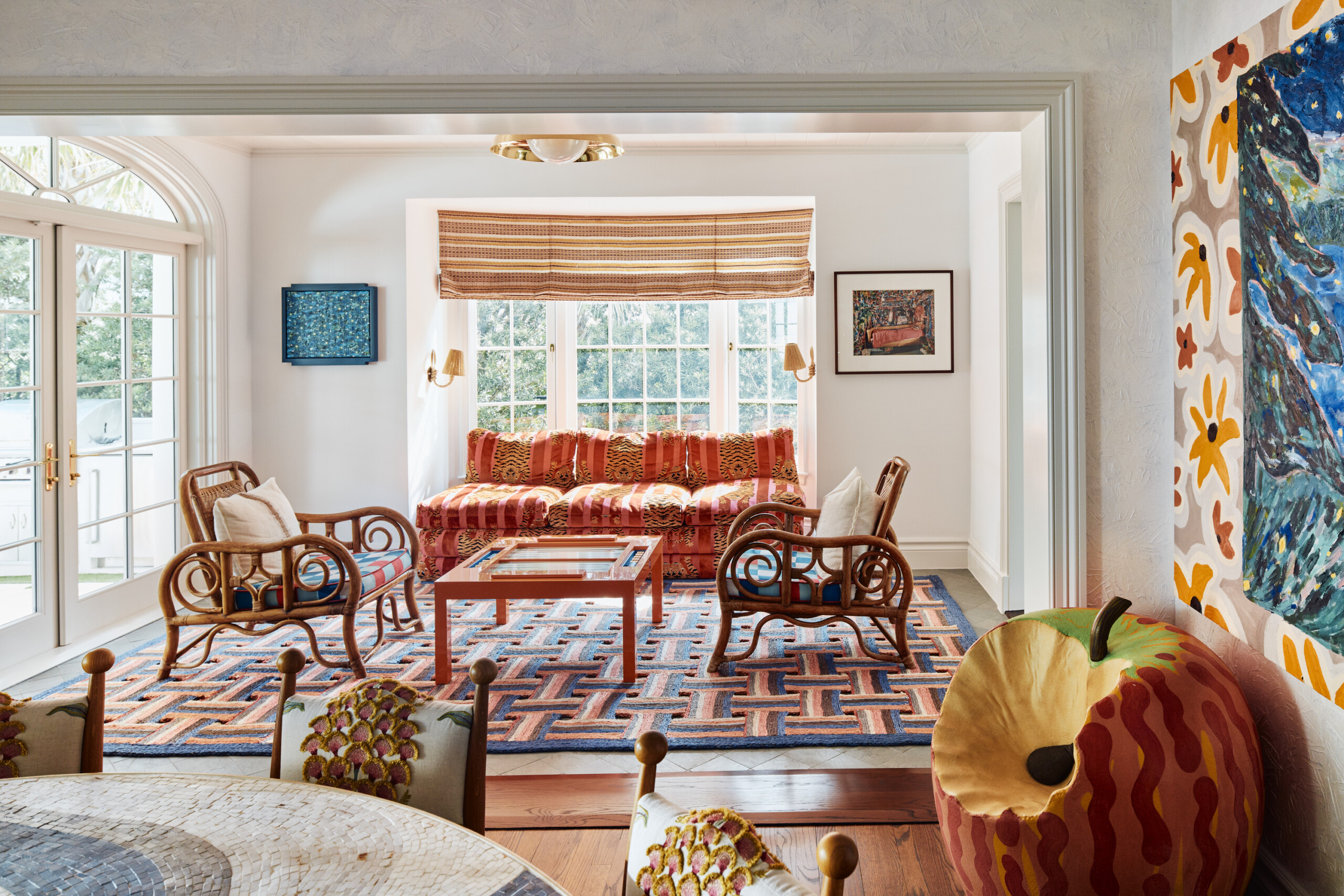 Palm Beach Interior Design by Pembrooke & Ives. Sunroom with vibrant sofa, rattan loungers, and...