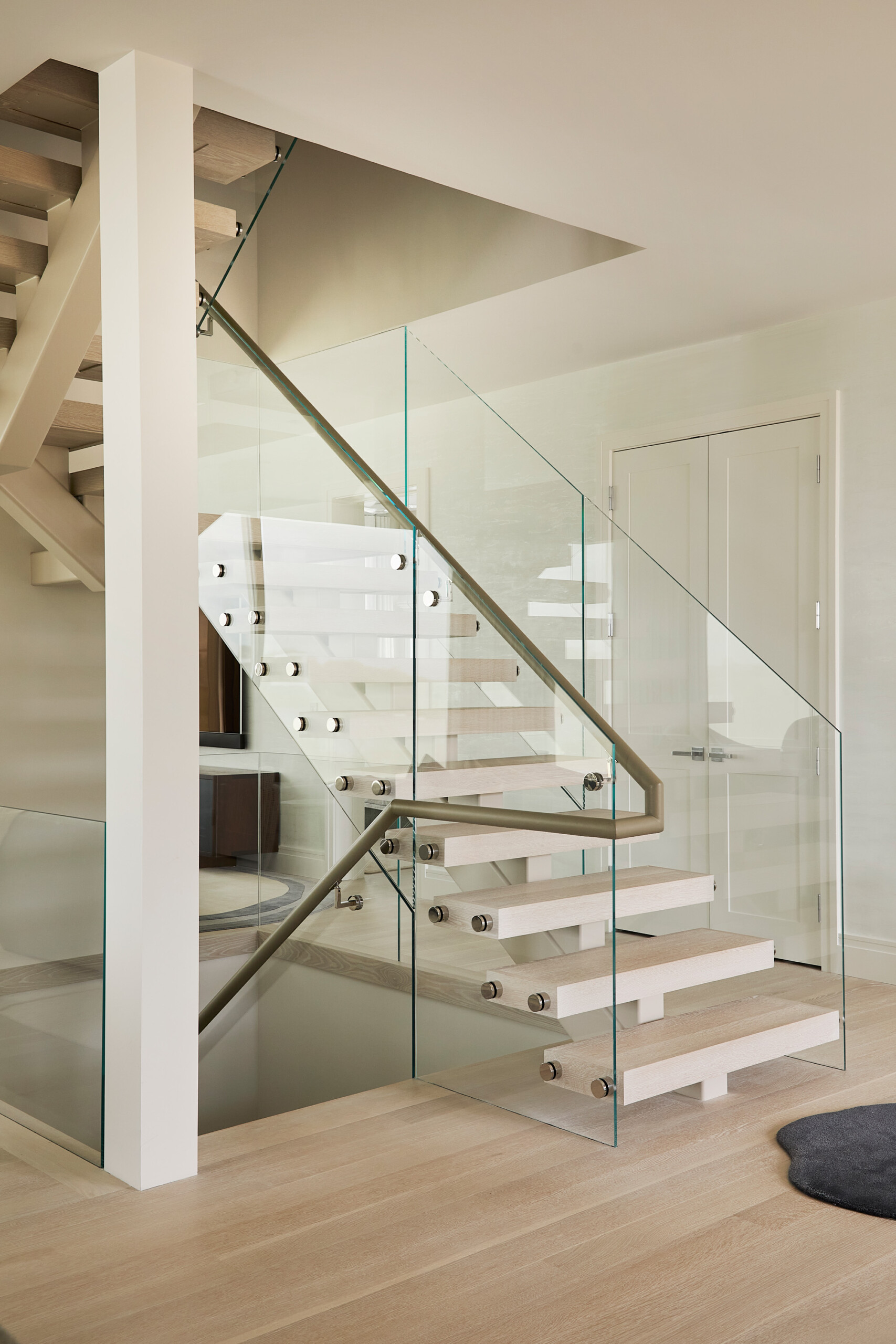 Hamptons Interior Design by Pembrooke & Ives. Modern glass, white oak, and metal staircase.