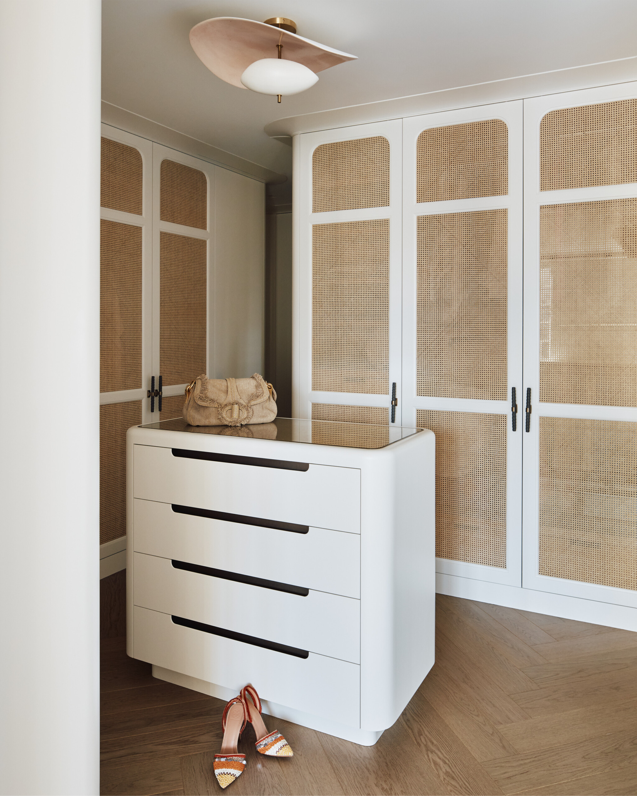 New York City interior design by Pembrooke & Ives. Primary suite closet with custom white and cane...