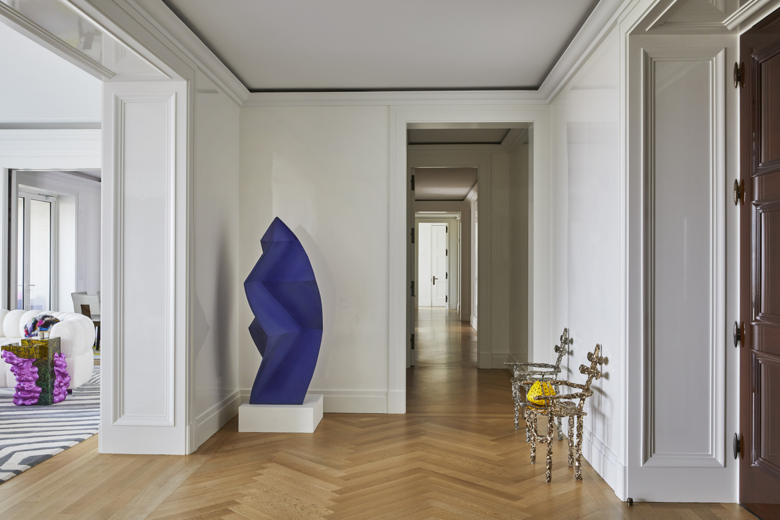 Hallway of Central Park South apartment with herringbone floors and an art sculpture. Interior...