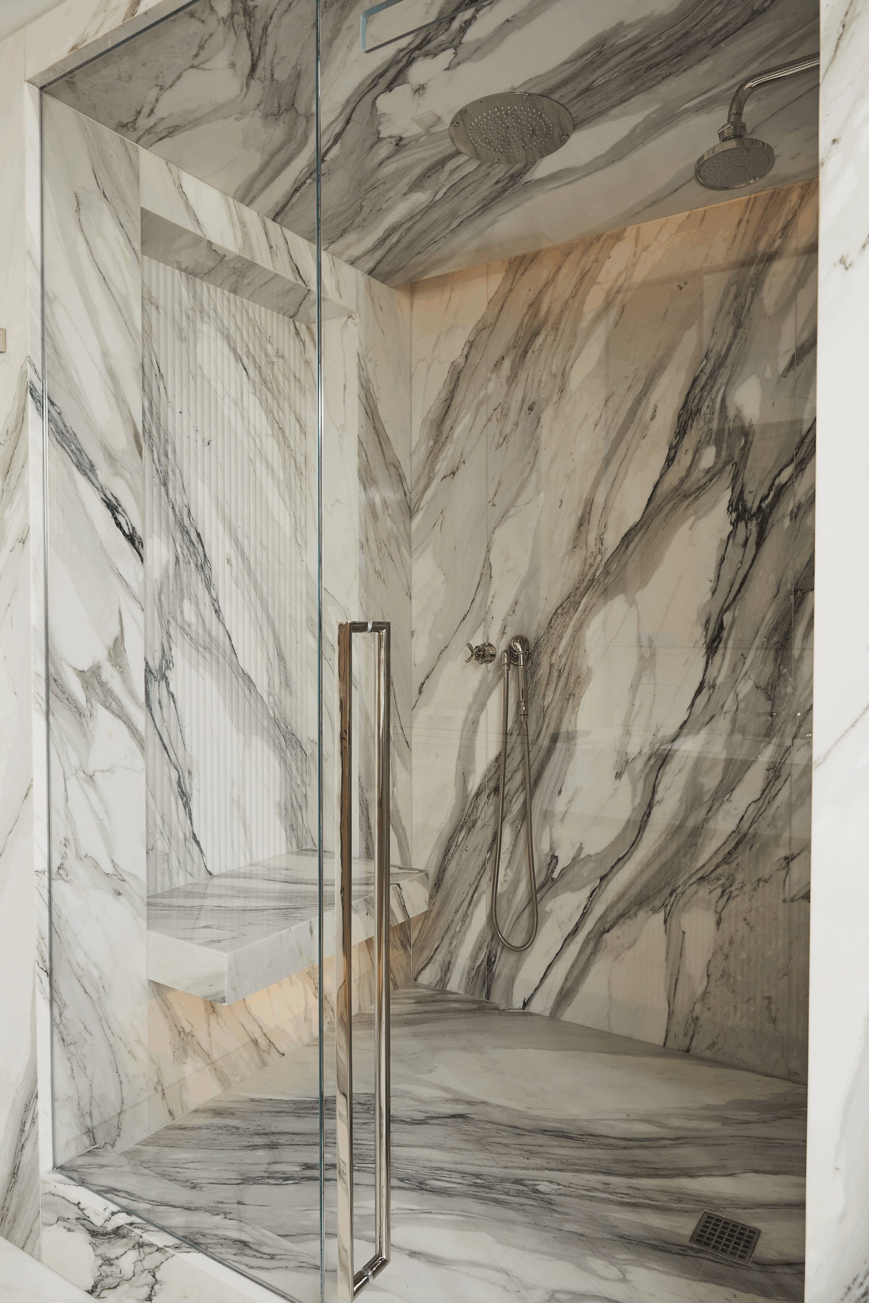 Marble-clad shower in the Turtle Bay Pied-a-Terre primary bathroom. Photography by Genevieve Garruppo....