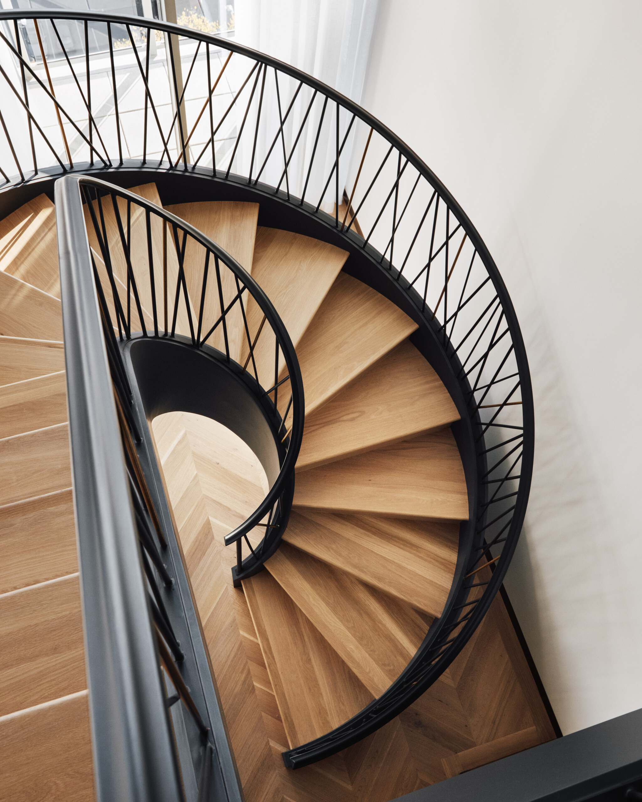 A detail shot of the spiral staircase in the Music Row Duplex showing white oak steps and blackened...